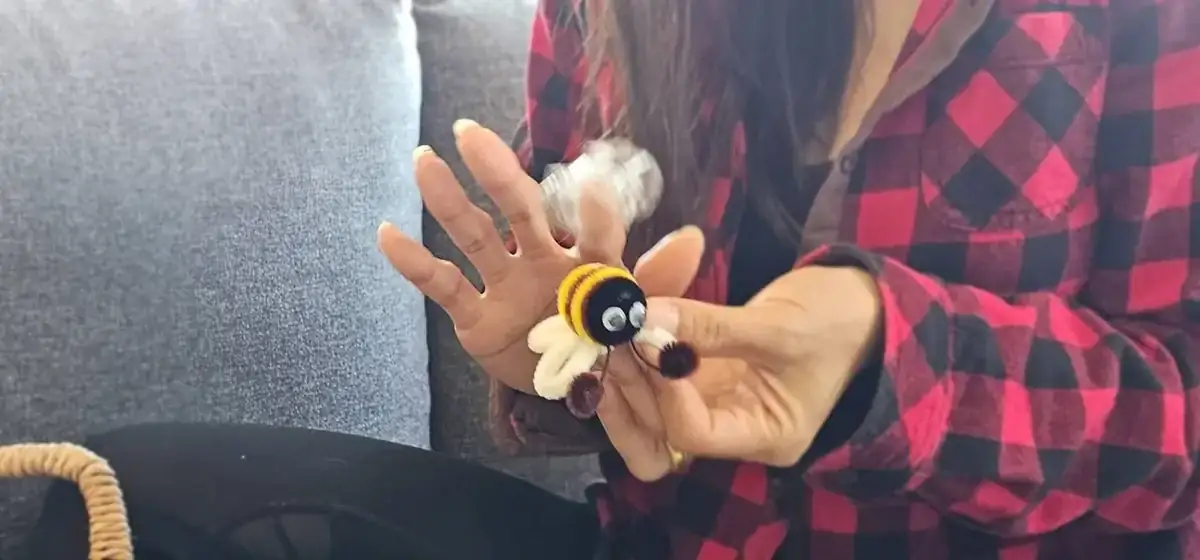 Single handmade pipe cleaner bee held gently showing craftsmanship