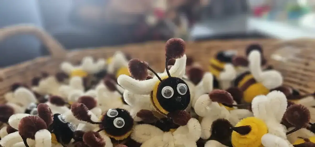 Close-up of handmade pipe cleaner bees with white wings in wicker basket