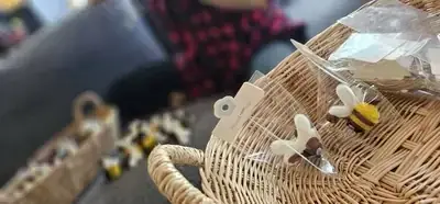 Gift-packaged handmade bee with tag displayed on wicker basket